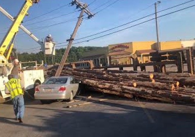 Philadelphia Utilities workers try to work on a power pole that was knocked down after a log truck overturned Monday morning.