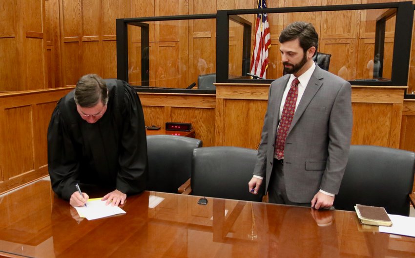 Senior Circuit Judge Mark S. Duncan signs the official paperwork after swearing in Judge Caleb E. May last Wednesday at the Neshoba County Courthouse.