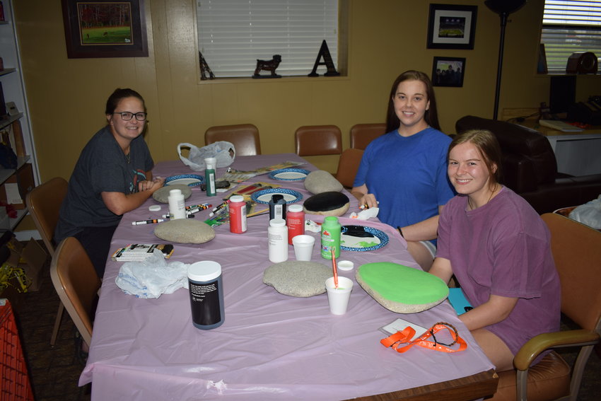 Random Acts of Kindness Painting rocks Grace Addy on left side of table and Emma Taylor in blue on right side next to sister Maggie Taylor