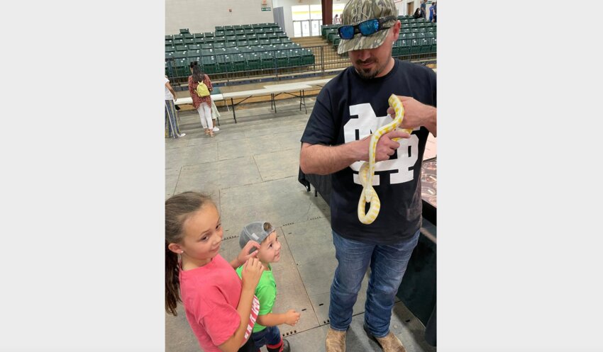 Hugh Johnson II is handling an albino python with his daughter, Cate Johnson, 7, and 2 year old son, Trace Johnson.